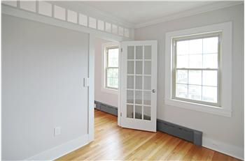 an empty room with white walls and wood floors