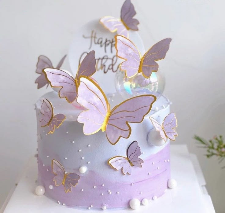 a white cake with purple butterflies on it's top and the words happy birthday