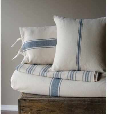 two white and blue striped pillows stacked on top of each other next to a wooden box