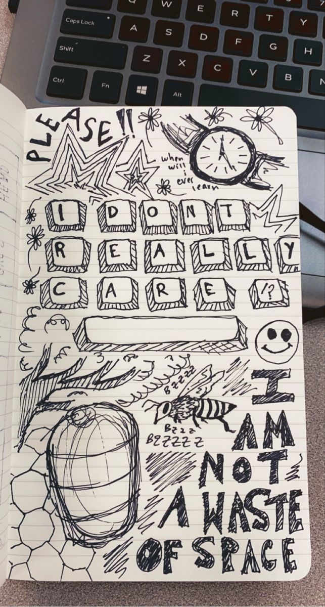 an open notebook with doodles on it next to a laptop