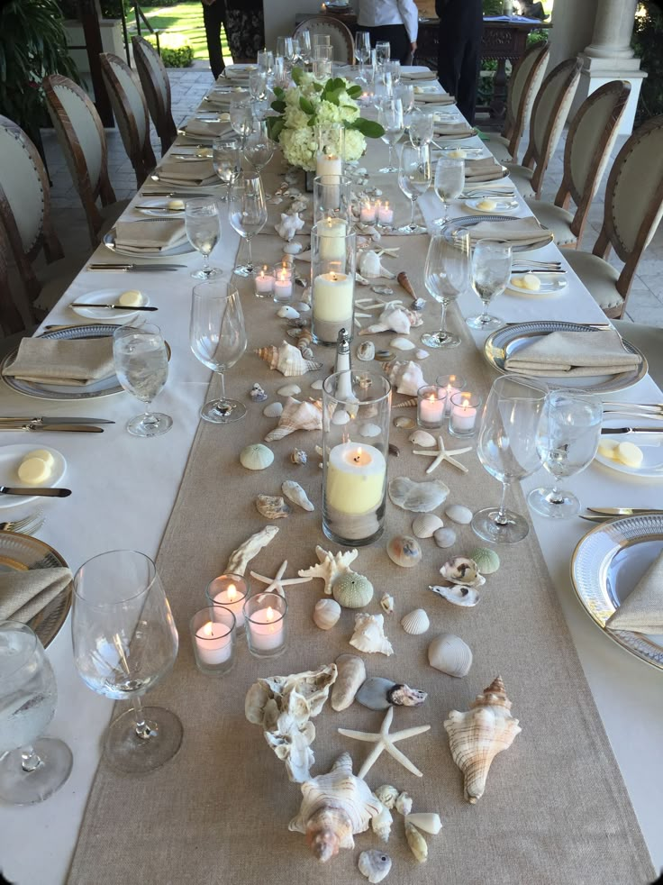 a long table is set with candles and seashells