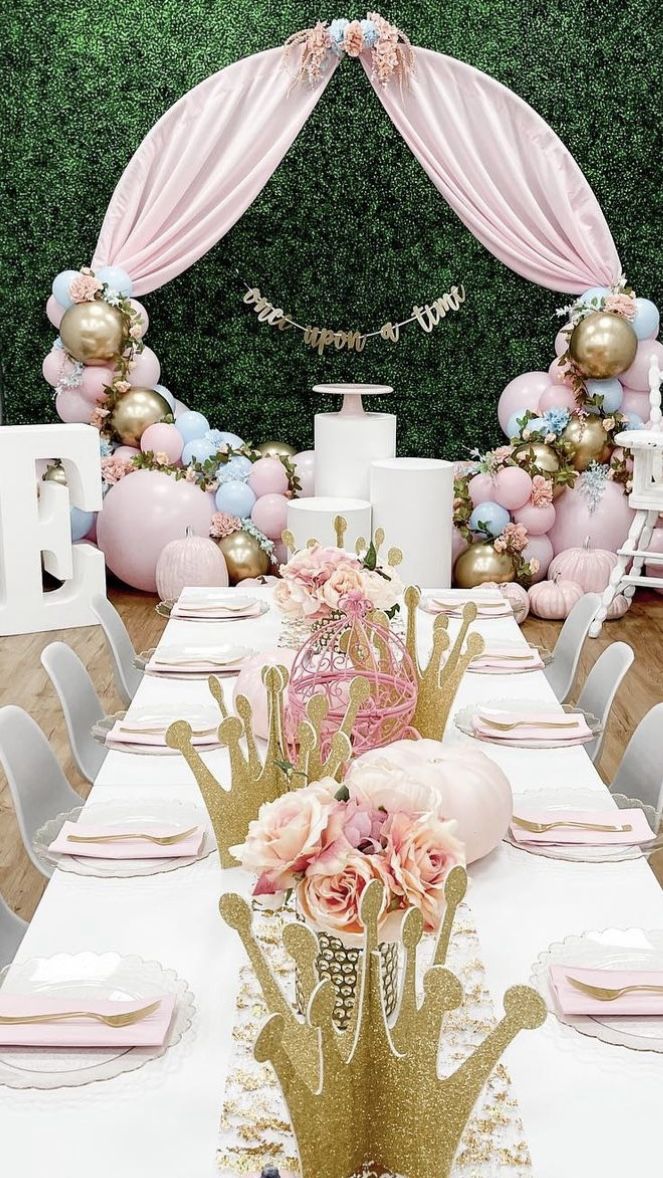 a table set up for a party with pink, gold and white decorations on it