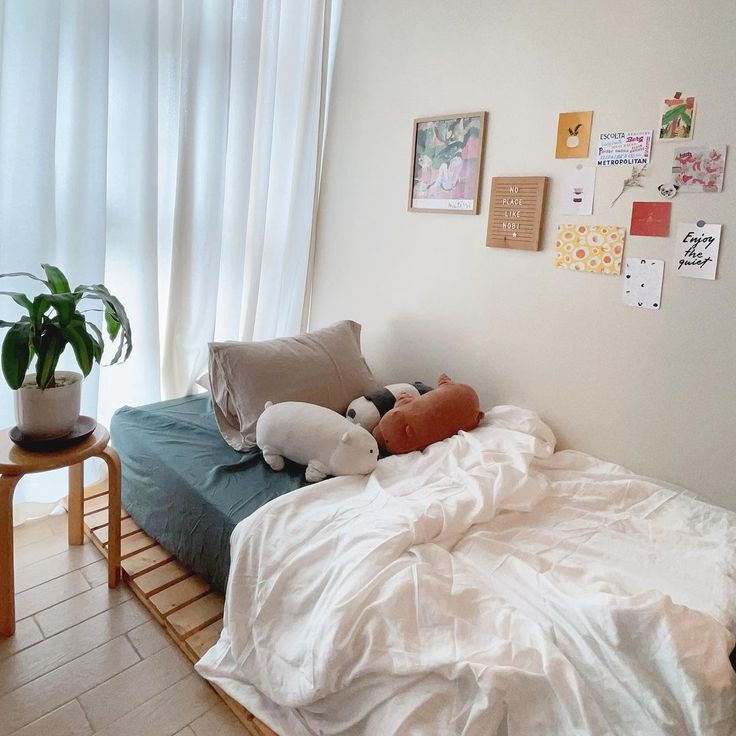 a bed with pillows and stuffed animals on it next to a window in a room