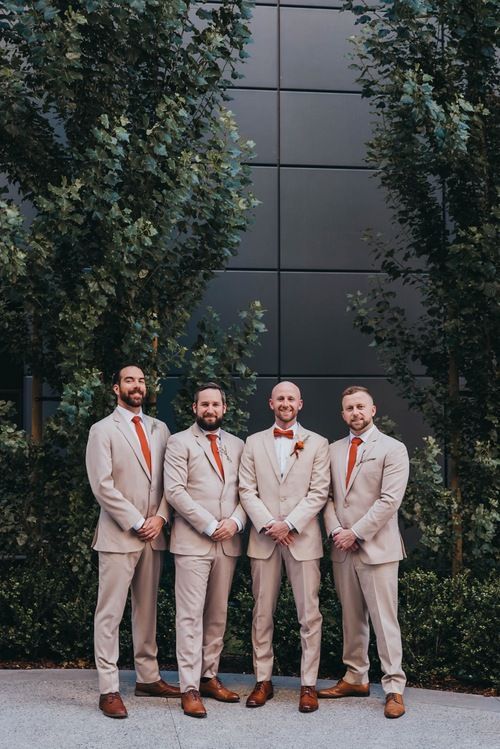 three men in tan suits standing next to each other