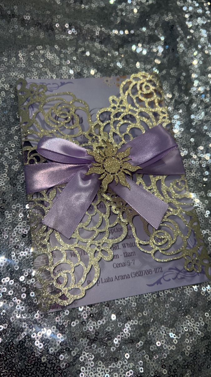 a purple and gold wedding card on sequins with a ribbon tied around it