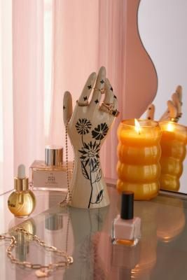 an assortment of perfumes and hand decorations on a table with a mirror in the background