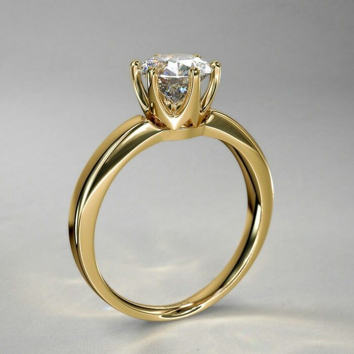 a yellow gold engagement ring with a single diamond in the center, on a white background