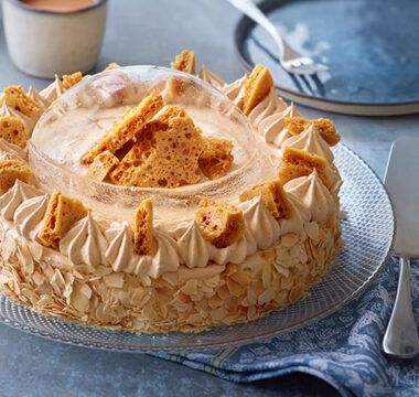 a cake sitting on top of a glass plate covered in frosting next to silverware