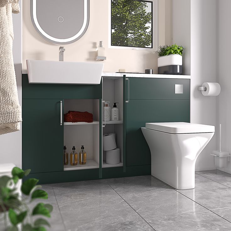 a white toilet sitting next to a green cabinet in a bathroom under a mirror above a sink