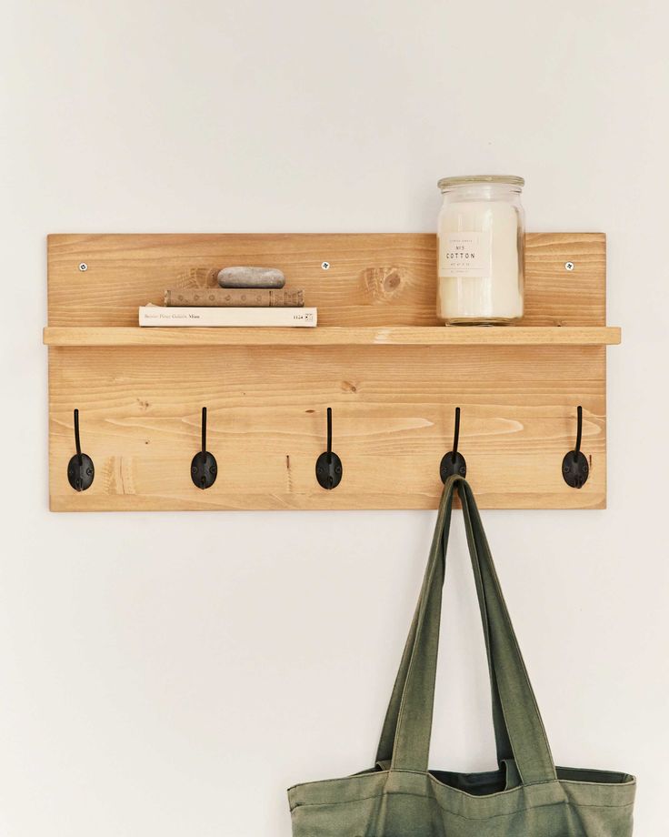 a bag hanging on a wall next to a pair of hooks and a book shelf