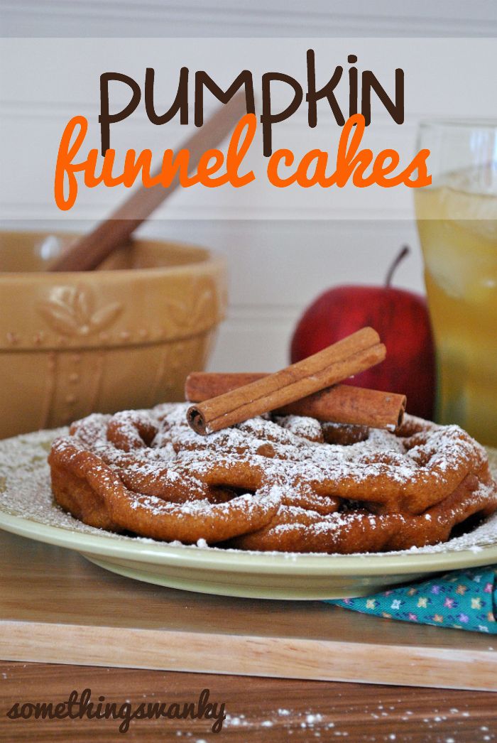 pumpkin funnel cakes on a white plate with cinnamon sticks and apples in the back ground