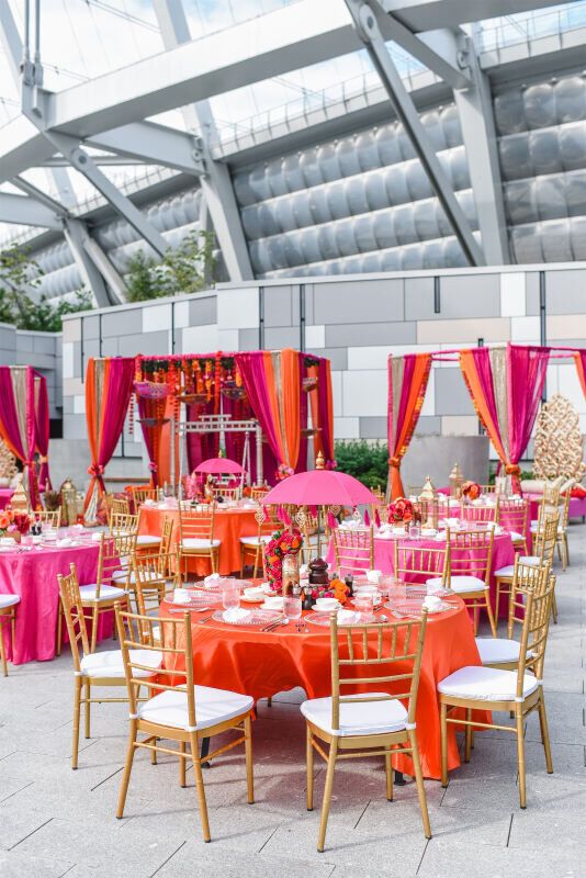 an outdoor event with tables and chairs covered in pink, orange and gold linens