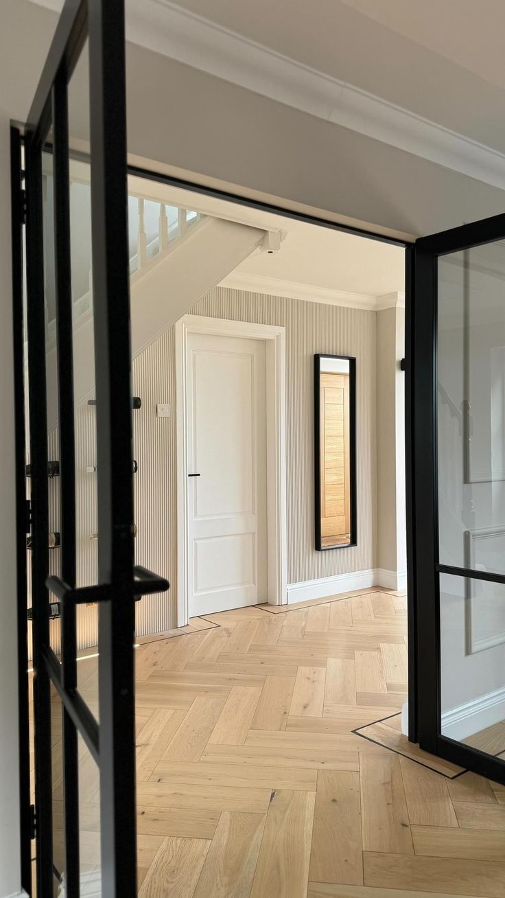 an empty room with wooden flooring and white walls is seen through the glass doors