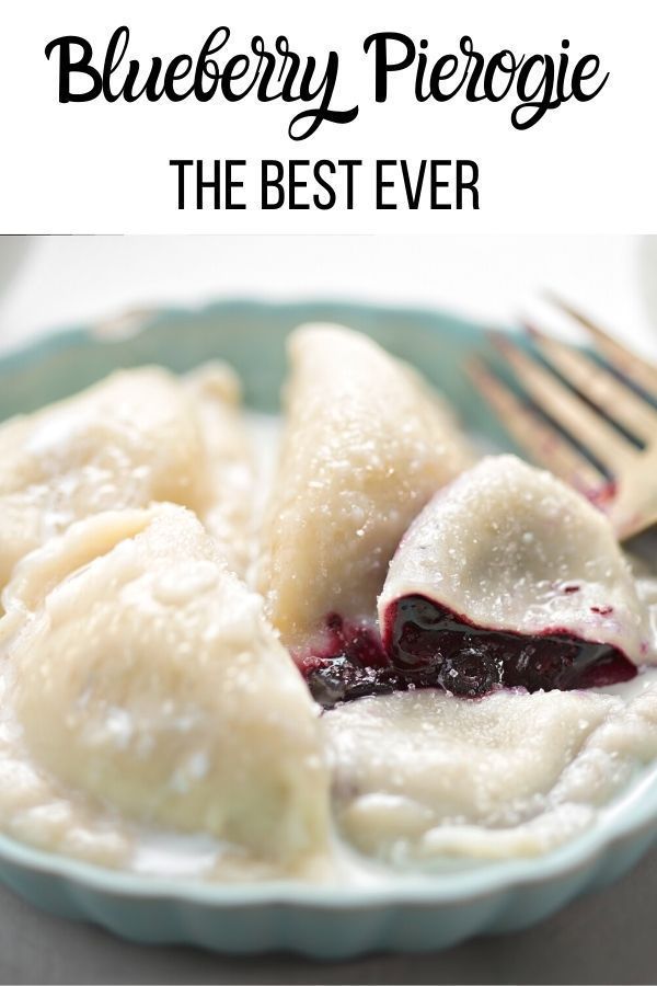 a blue plate topped with dumplings covered in cheese and jelly next to a fork