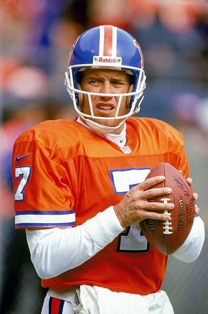 a man in an orange and white uniform holding a football