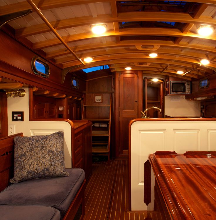 the inside of a boat with wood flooring and wooden walls, lights are on