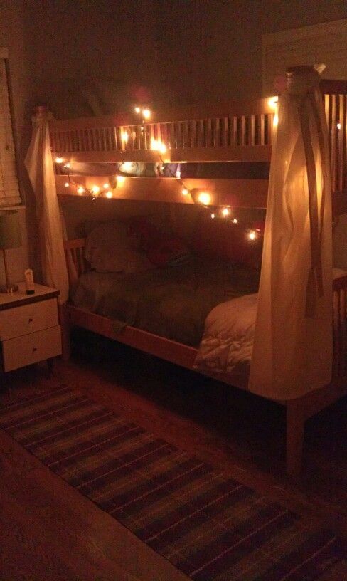 there is a bed with lights on it and a rug in front of the bed