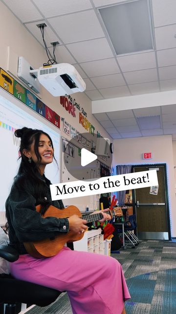 a woman sitting in a chair holding a guitar with the words move to the beat on it