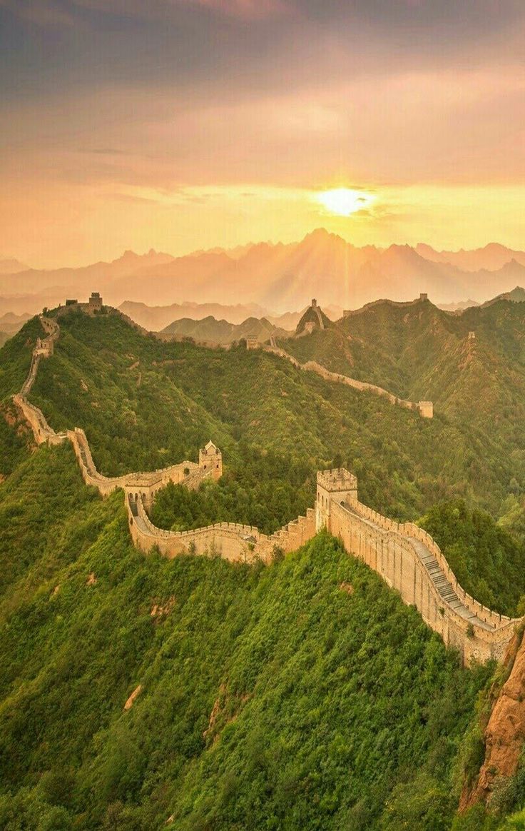 the great wall of china at sunset, with mountains in the background