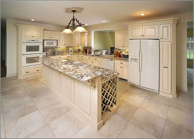 a large kitchen with marble counter tops and white cupboards, along with an island in the middle