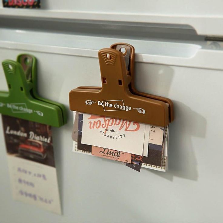 two magnets attached to the side of a white refrigerator freezer with brown and green clippings