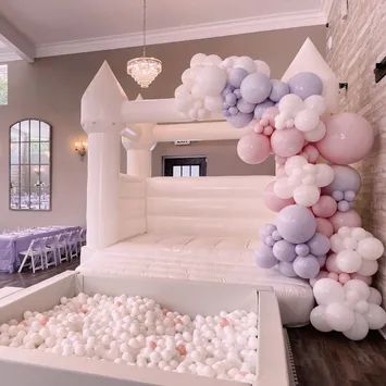 a balloon arch is decorated with pastel colors and white balloons in the shape of a castle