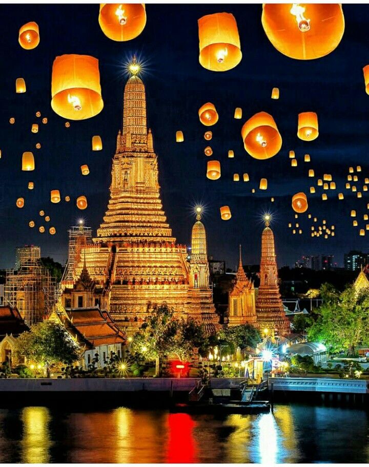 many lanterns floating in the air over water