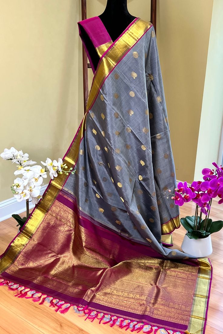 This stunning kanjivaram saree in english grey is handwoven. The bavanji borders have geometrical patterns in magenta pink in gold zari! This exquisite saree is adorned with chakram and peacock motifs in gold zari while the grand pallu with traditional annam motifs in gold zari. Truly a masterpiece! Approximate Length 6.25 - 6.50 mtrs (inclusive of blouse length) Approximate Height - 46 - 52” Saree comes with fall, picot and tassels done when applicable . Blouse piece is cut. Approximate weight Peacock Motifs, Kanjivaram Saree, Kanjivaram Silk Saree, Silk Cotton Sarees, Kanjivaram Sarees, Magenta Pink, Cotton Sarees, Blouse Length, Support Team