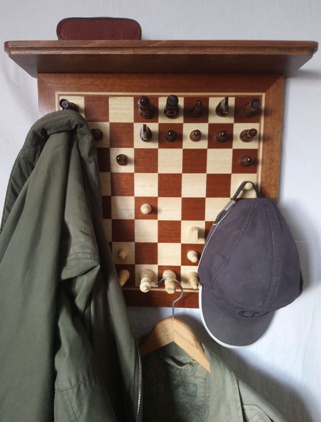 a hat and jacket hang on the wall next to a chess board