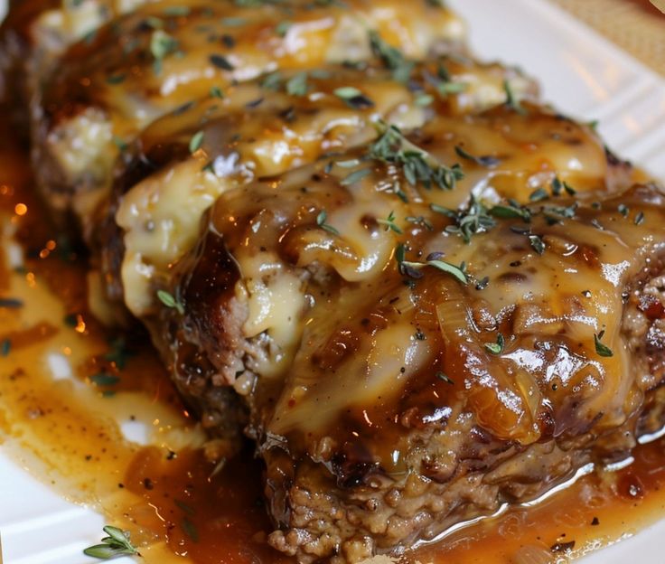 a plate with meat covered in gravy and garnished with fresh herbs