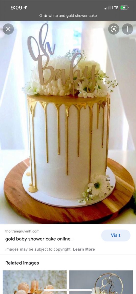 a baby shower cake with gold drips and white flowers on the top is featured in an instagram