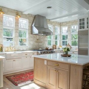 a large kitchen with white cabinets and wood flooring on the walls, along with an island in the middle