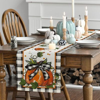 a dining room table set with pumpkins, candles and plates on the wooden table