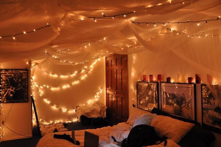 a bedroom with lights strung from the ceiling and pictures hanging on the wall above it