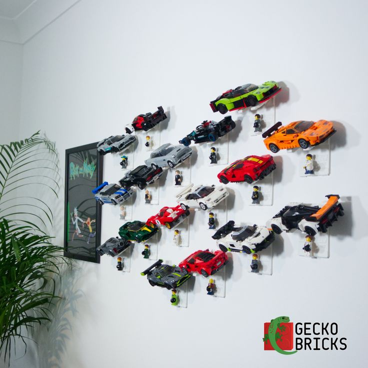 there are many toy cars hanging on the wall next to a potted green plant