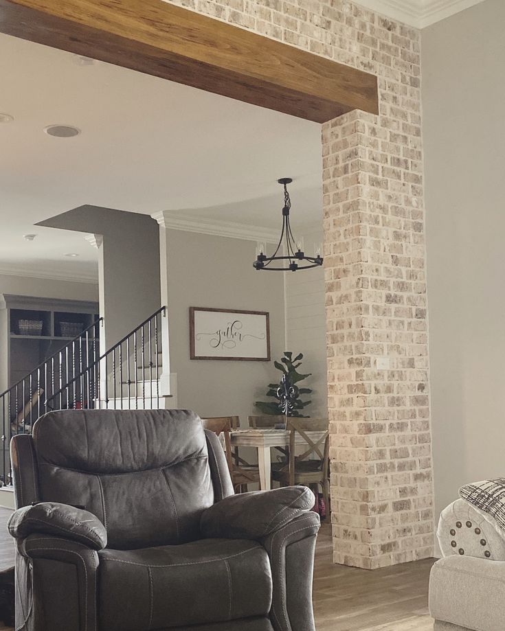 a living room filled with furniture next to a brick wall and wooden beams on the ceiling