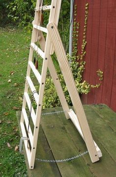 a wooden ladder sitting on top of a grass covered field next to a red building