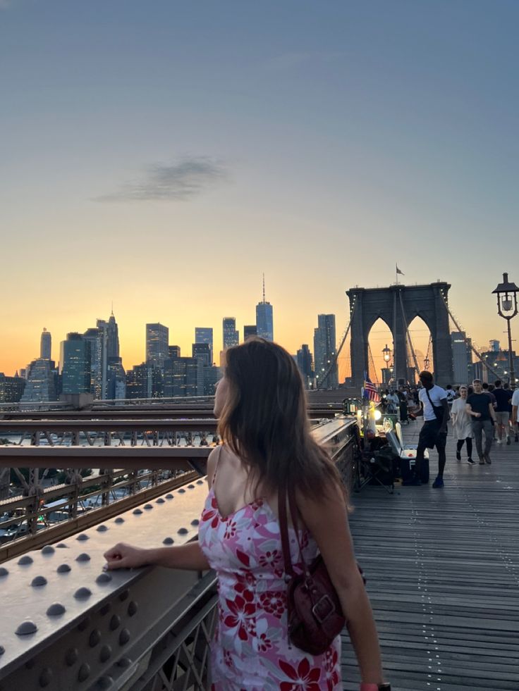 a woman standing on a bridge looking at the city