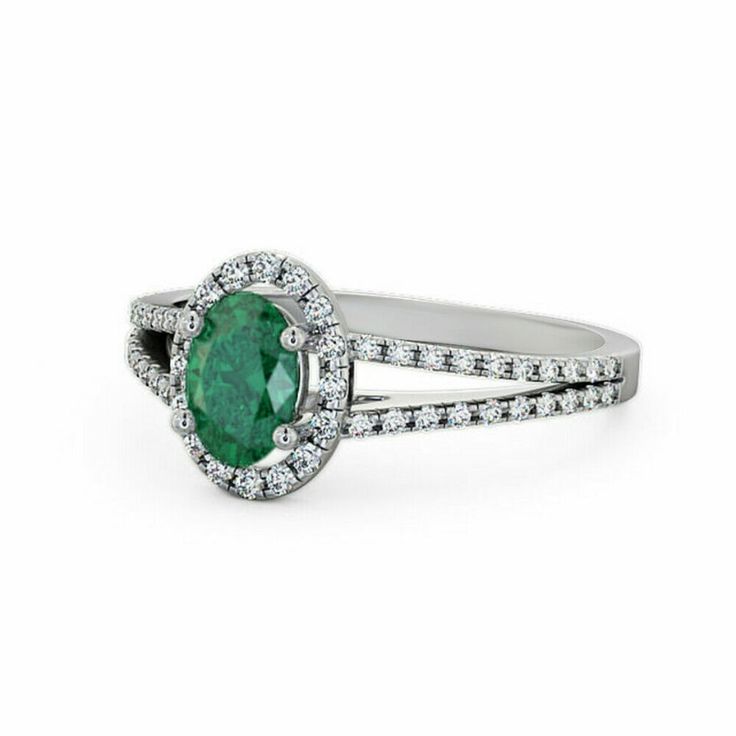 an oval shaped emerald and diamond ring with split shans on the sides, set in 18k white gold