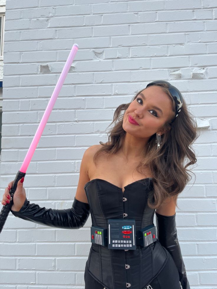 a woman in a cosplay holding a pink light saber