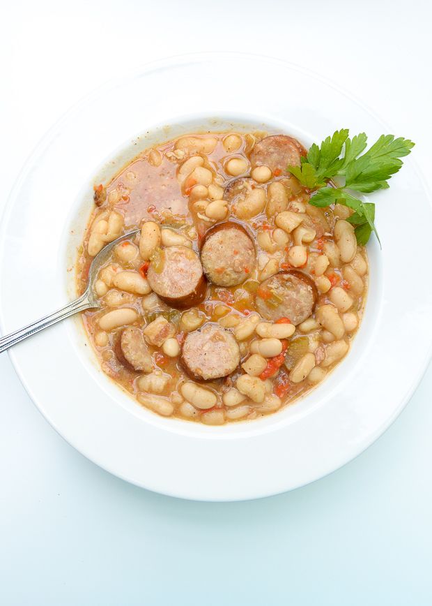 a white bowl filled with beans and sausage