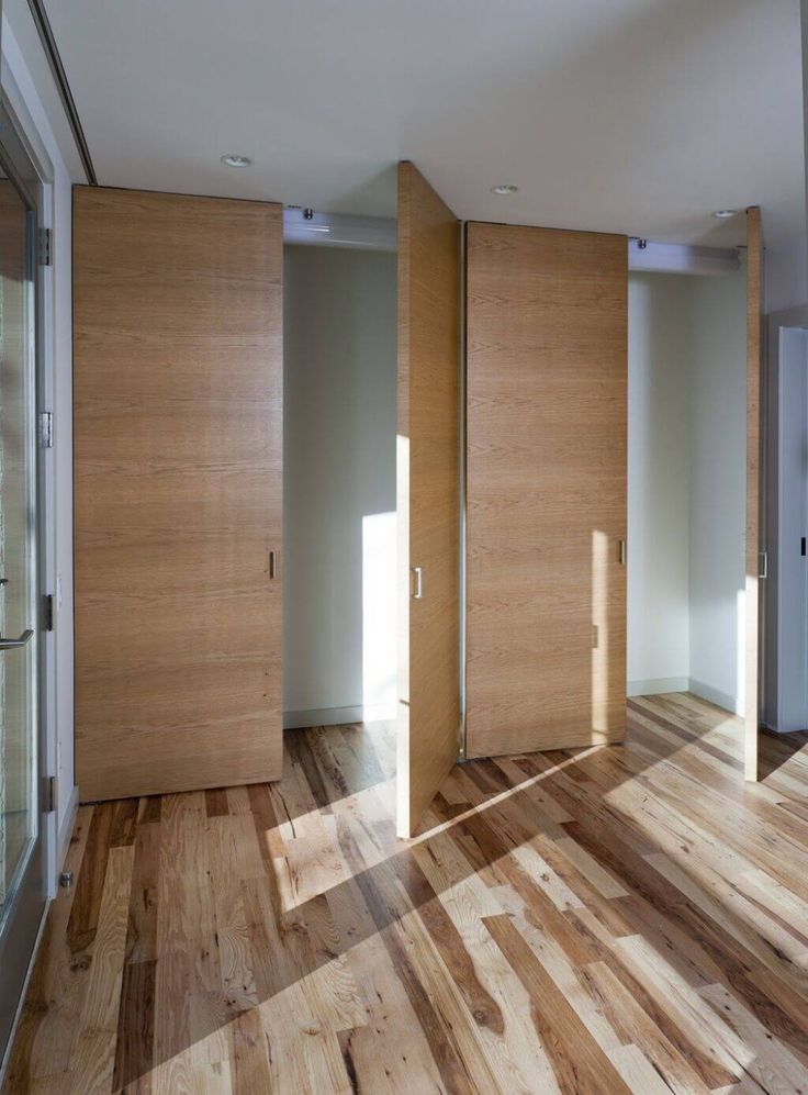 an empty room with wooden doors and hard wood flooring