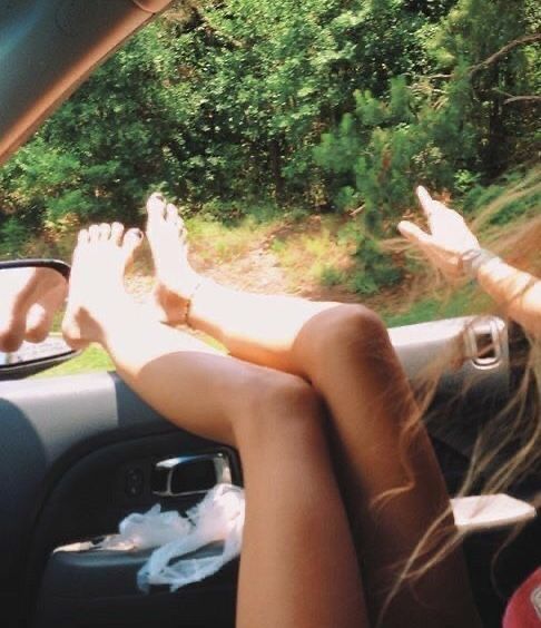 two people sitting in the back seat of a car with their feet on the dashboard