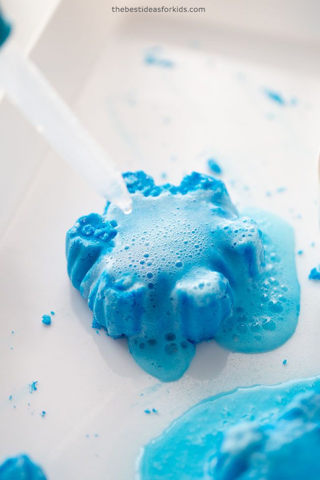 blue and white play dough on a plate with a plastic spoon next to it in the background