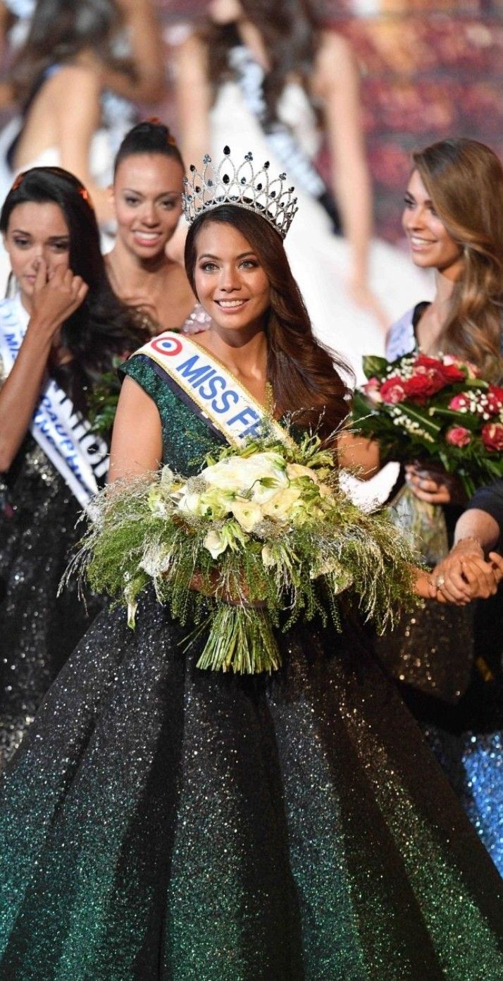 two beautiful women standing next to each other wearing crowns and gowns with flowers on them