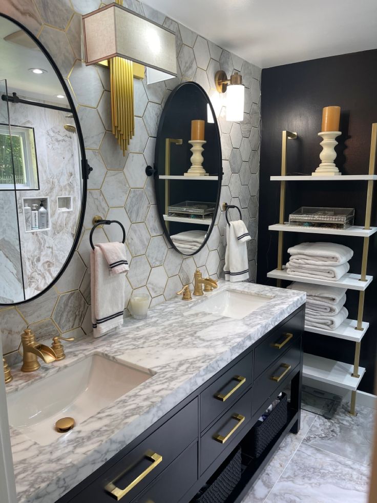 a bathroom with marble counter tops and gold accents on the wall, along with two round mirrors