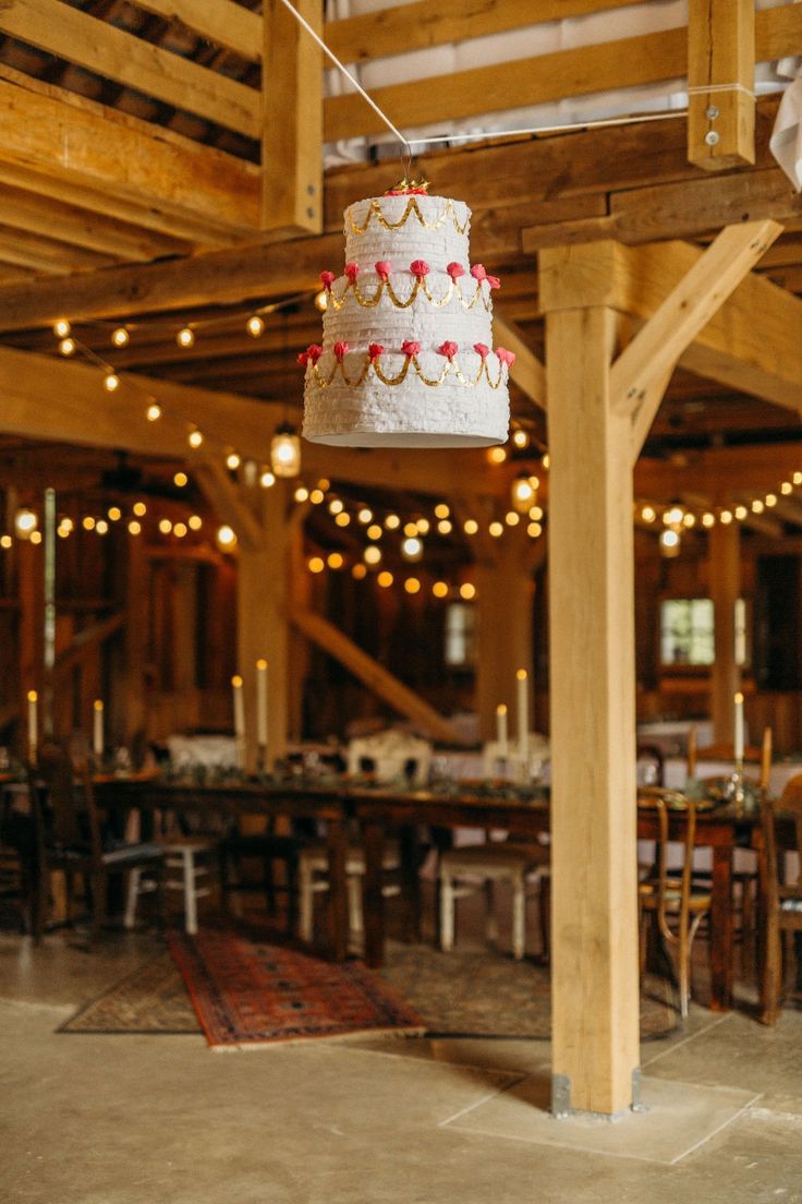 a wedding cake hanging from the ceiling in a large room filled with tables and chairs