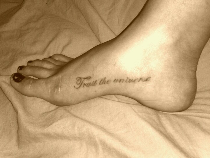 a person with a tattoo on their foot that says trust the universe in cursive writing