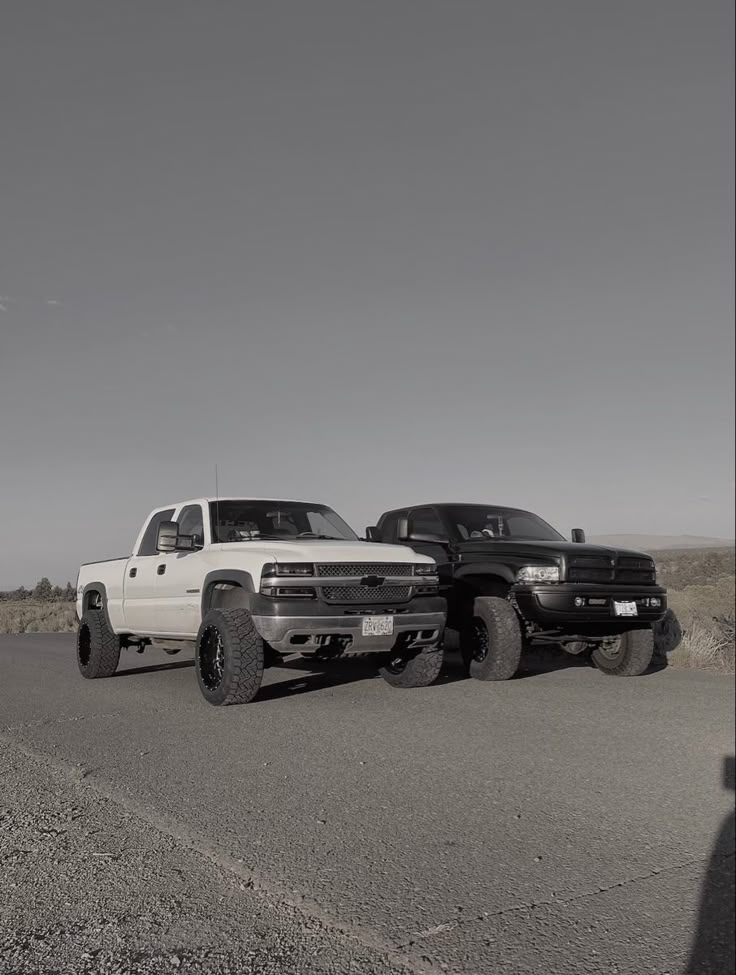 two pickup trucks are parked on the side of the road