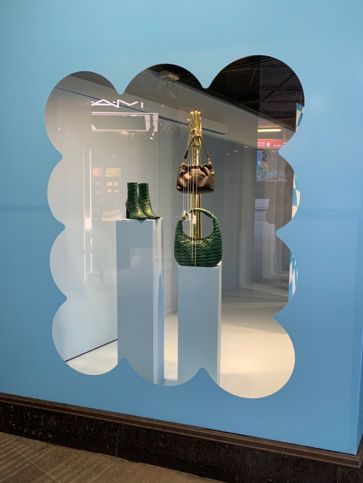 a window display with shoes and purses on pedestals in front of a blue wall